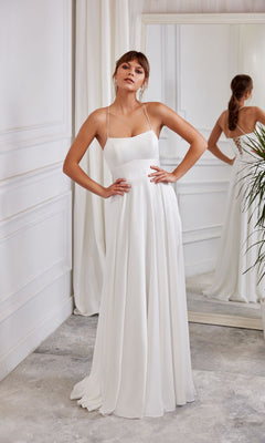 A woman poses hands-on-hips in a minimalist room, wearing the Aerie Couture 2005 long a-line dress in Diamond White, featuring thin straps and a sleeveless design.