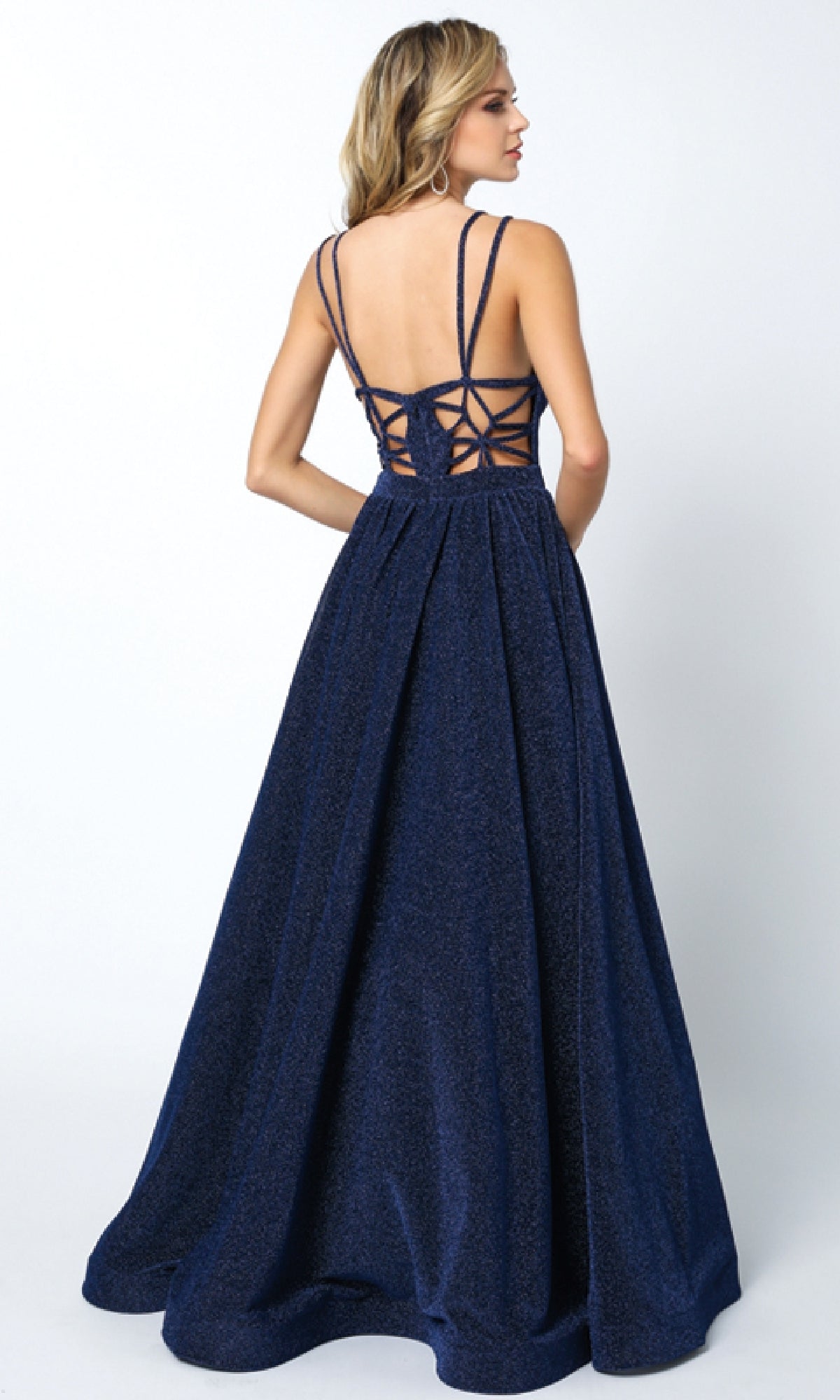 A woman in the Juliet 201 long prom dress, featuring navy blue fabric, double spaghetti straps, and a lace-up cut-out back, stands facing away against a plain background.