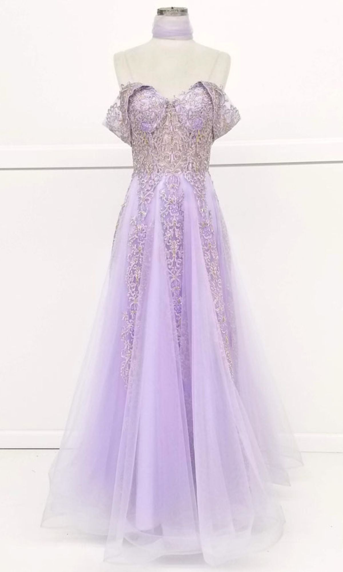 The Long Lace Prom Ball Gown: Chicas CA1103 is a light purple off-the-shoulder dress with a fitted ornate bodice and full tulle skirt, shown on a dress form against a plain white background.