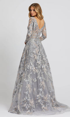 A woman models the Long Sleeve Long Formal Dress: Mac Duggal 20214—a floor-length, silver-gray gown with floral patterns, long sleeves, and a low-cut back—against a plain background.