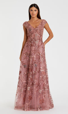 A woman models the Cap-Sleeve Long Print Prom Dress by Mac Duggal 20263, a floor-length rose gown with floral embroidery and a V-neckline, standing against a plain white background.