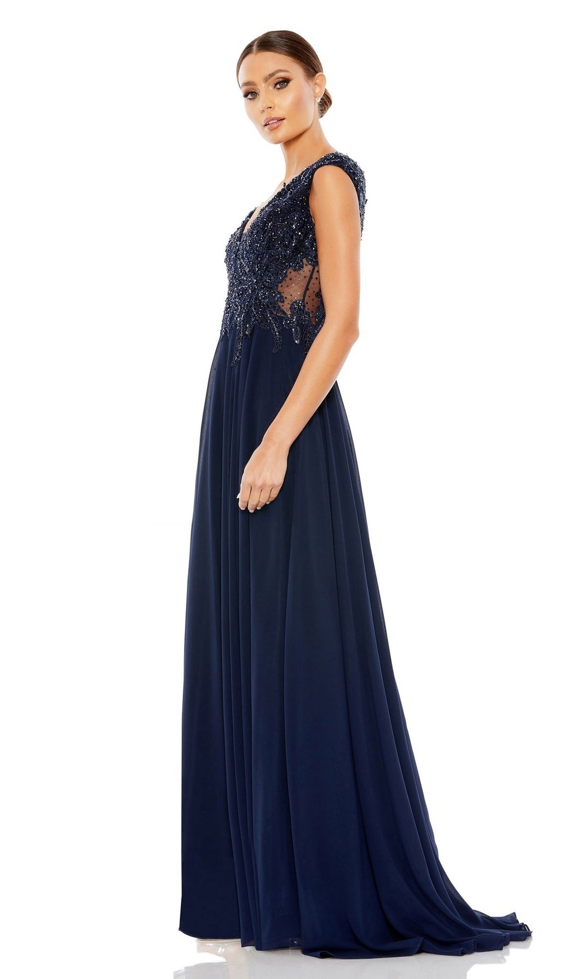 A woman models the Mac Duggal 20264 Beaded-Bodice Long Formal Dress—navy blue with lace accents, a beaded v-neck bodice, sheer side panels, and floor-length skirt—posed against a white background.
