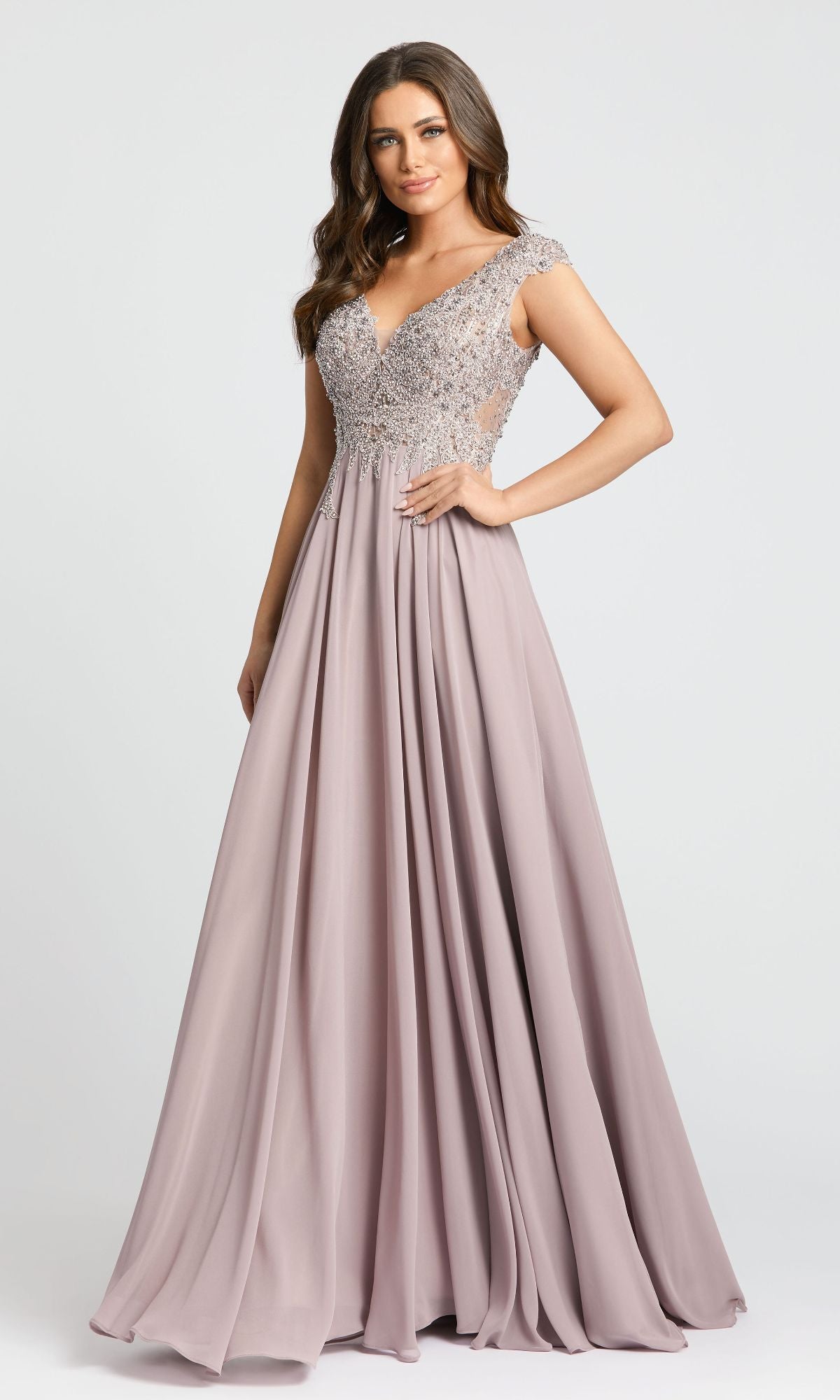 A woman in the Mac Duggal 20264 Beaded-Bodice Long Formal Dress, featuring a mauve floor-length A-line skirt, beaded v-neck bodice, and cap sleeves, stands against a plain light background.