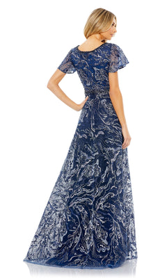 A woman poses from the back in the Mac Duggal 20301 short-sleeve formal dress, featuring a floor-length design with silver embroidery and a beaded waist.