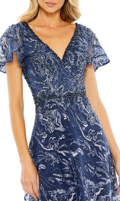 A woman wearing the Mac Duggal 20301 short-sleeve formal dress in navy blue, featuring a deep V-neck, beaded waist, and intricate sequin patterns.