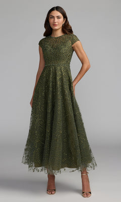 Woman wearing an olive Tea Length Lilac Party Dress, style Mac Duggal 20338, featuring cap sleeves and intricate beaded embroidery, posing against a plain gray background.