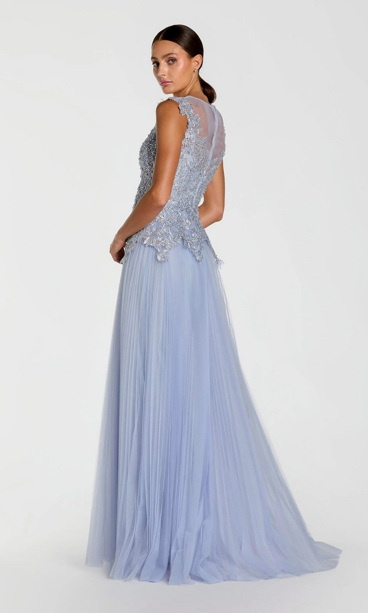 A woman stands with her back turned, looking over her shoulder in the Long Formal Dress: Mac Duggal 20360, a sleeveless light blue lace and tulle A-line gown, against a plain white background.