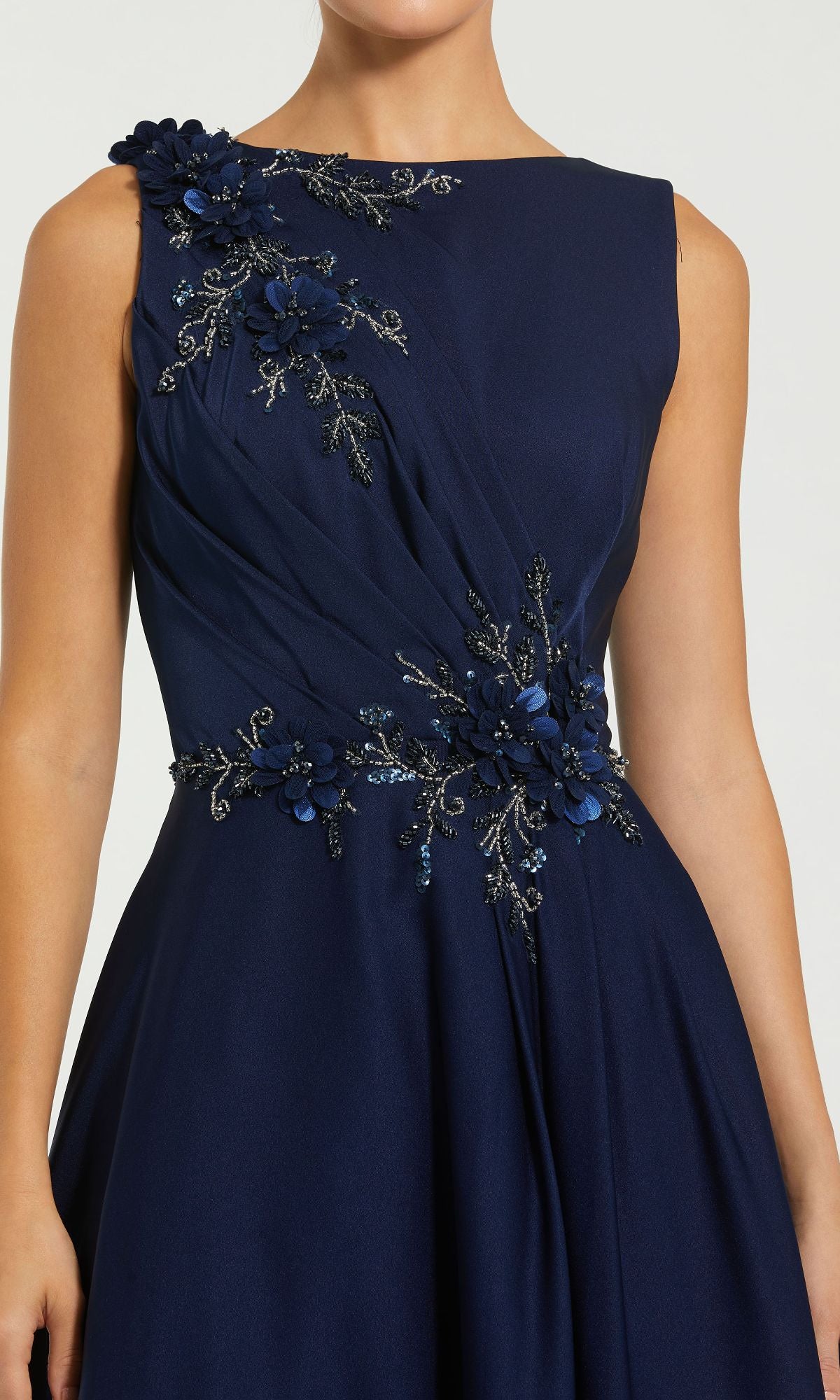 Woman wears the Mac Duggal 20365 Sleeveless Long Formal Dress in navy, featuring floral appliqué and beaded embellishments on the shoulder and waist—a sophisticated choice for evening events.