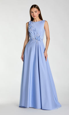 A woman wears the Mac Duggal 20365 sleeveless long formal dress, featuring a floor-length light blue skirt and beaded floral embroidery on the bodice, standing against a plain light background.