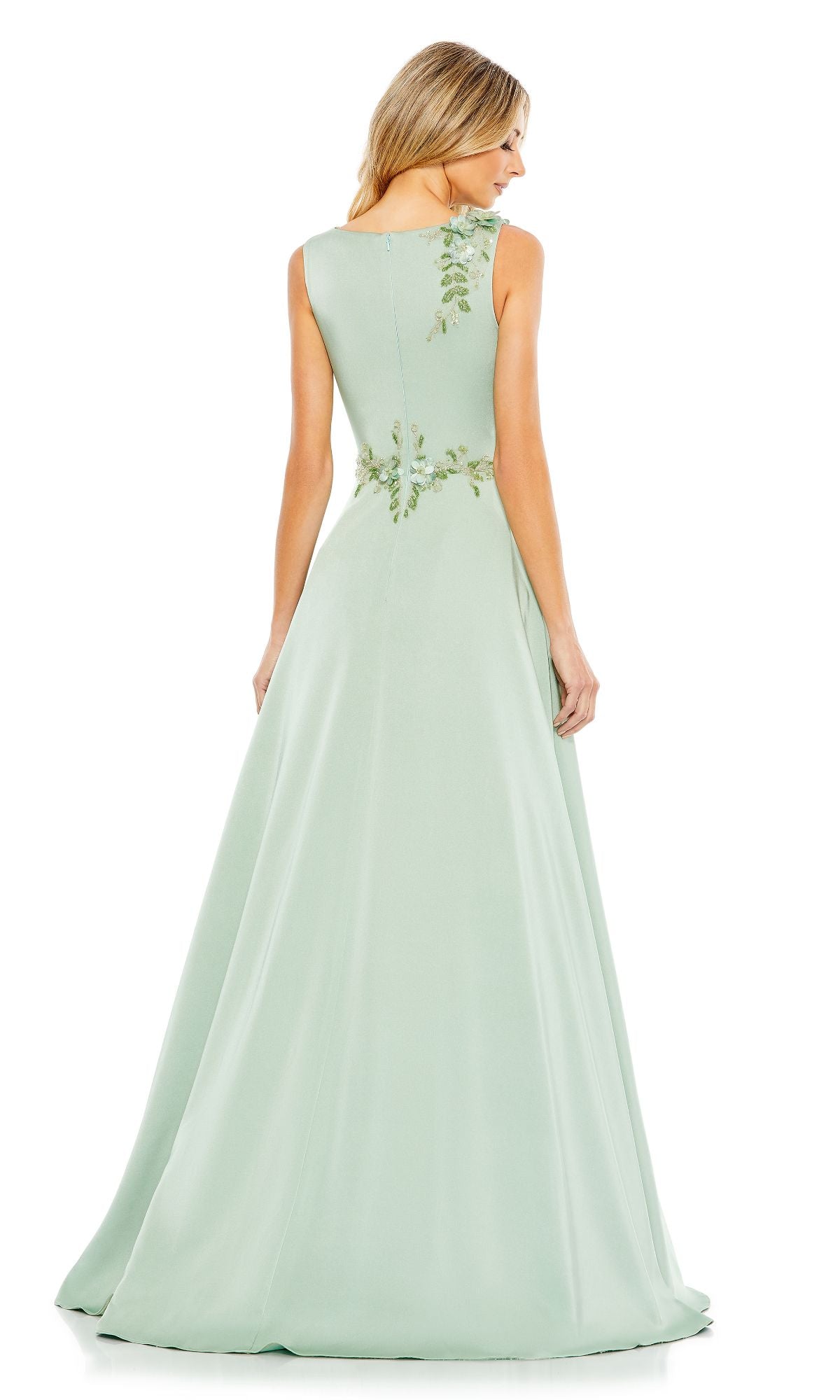 A woman faces away, wearing the Mac Duggal 20365 Sleeveless Long Formal Dress in pale green with subtle floral embroidery at the back and waist, capturing the gown's elegant evening look.