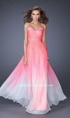 A woman stands against a plain gray background wearing the Floor Length La Femme Formal Dress—a strapless, sweetheart neckline gown with a pink-to-white ombre, fitted beaded bodice and flowing skirt.
