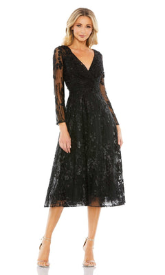 A woman wears the Mac Duggal Sleeved Black Wedding-Guest Dress 204041, featuring sheer long sleeves and lace detailing, paired with open-toe heels, against a white background.
