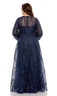 A woman stands facing away, modeling the Mac Duggal 20472— a long plus-size formal dress in navy blue, featuring sheer sleeves, intricate sequin details, and delicate floral embroidery along the v-neckline, set against a plain white background.