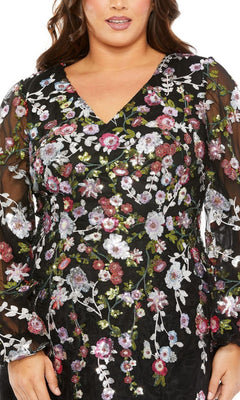 A person wearing the Plus-Size Semi-Formal Dress 20474 by Mac Duggal, featuring a black long sleeve midi silhouette with colorful floral embroidery, sheer sleeves, and a V-neckline.