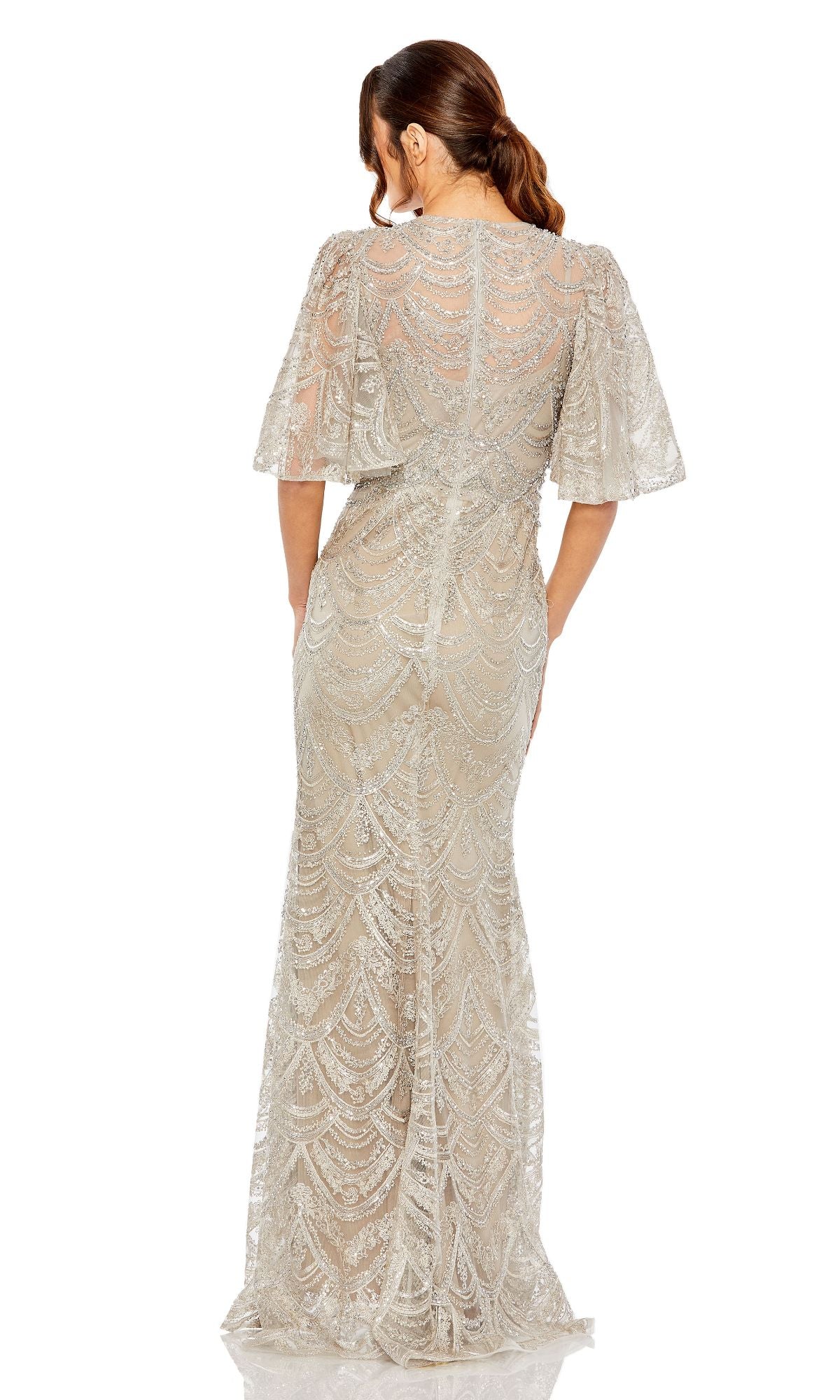 A woman, hair in a ponytail, faces away wearing the Mac Duggal 20481 Flutter-Sleeve Taupe Formal Gown with scalloped patterns and flutter sleeves, creating an elegant and sophisticated look.
