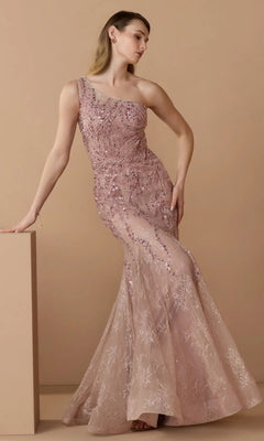 A woman models the Mac Duggal 20482 long formal dress in rose, a one-shoulder, floor-length mermaid gown with sequin and embellished lace details, set against a beige background.