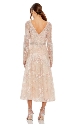 A woman faces away, wearing the Mac Duggal 20489 pale pink floral embroidered mesh long sleeve midi wedding guest dress with a V-back and silver heels.