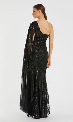 A woman models the Mac Duggal 20528 One-Shoulder Long Prom Gown—a floor-length black sequin dress with sheer draped detailing—standing against a plain white background.