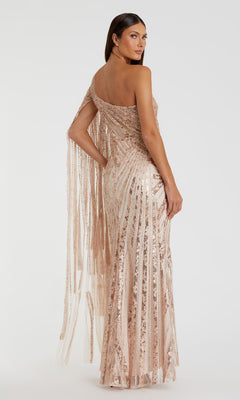 A woman models the Mac Duggal 20528 one-shoulder long prom gown in rose gold sequins with vertical stripes and fringe on one sleeve, standing against a plain white background.