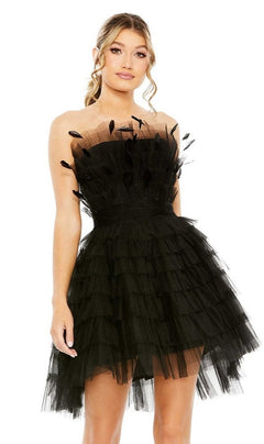 A woman in the Mac Duggal 20529 Strapless Ruffle Party Dress, featuring black tulle tiers and feather-like embellishments, stands against a plain white background.