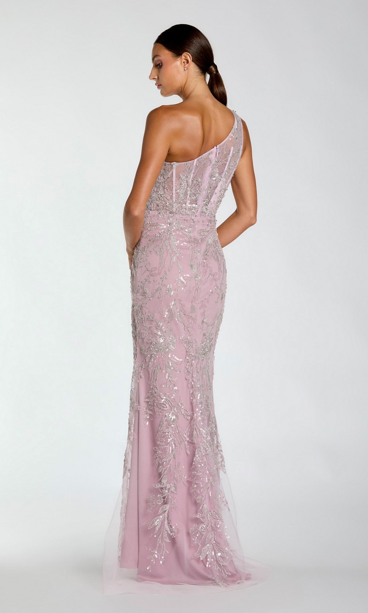 A woman models the Mac Duggal 20543, a light pink one-shoulder long formal dress with silver sequins, seen from the back against a plain white background.