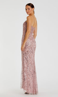 A woman poses gracefully in the Strapless Long Beaded Prom Dress by Mac Duggal (style 20544), a floor-length, light pink gown, looking over her shoulder against a plain white background.
