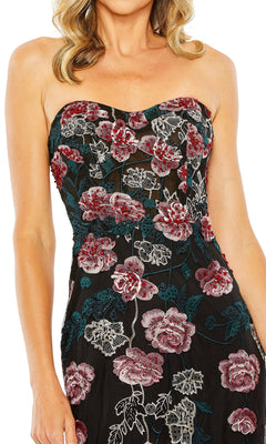 A woman wears the Long Formal Dress 20581 by Mac Duggal, a strapless fitted gown with red, pink, and green floral embroidery. The sweetheart neckline flatters her upper body; her face is partially out of frame.