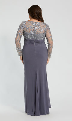 A woman wears the Mac Duggal 20624 plus-size long gray formal dress, showcasing a fitted silhouette with sheer, embroidered sleeves and back, as she stands facing away from the camera.
