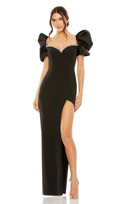 A woman models the Long Formal Dress 20687 by Mac Duggal—black, with puffed off-the-shoulder sleeves, a beaded sweetheart neckline, and a side slit—standing against a white background.