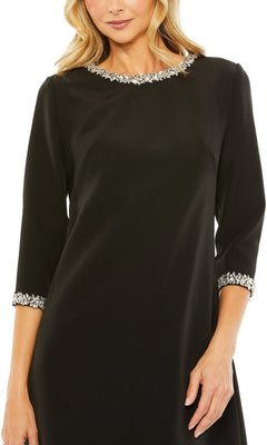 A woman wearing the Mac Duggal 20697 Short Wedding Guest Dress, featuring a black beaded scoop neckline, three-quarter sleeves, and silver-embellished cuffs.