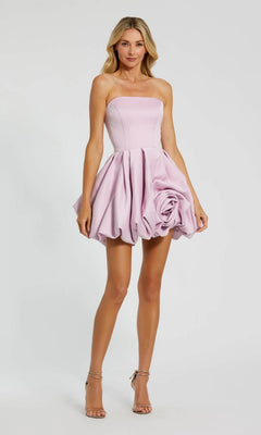 A woman stands against a plain background in the Mac Duggal 20705 Red Rose Bubble-Hem Hoco Dress, featuring a strapless design, vibrant red color, bubble skirt with a large rosette detail, and paired with nude high heels.