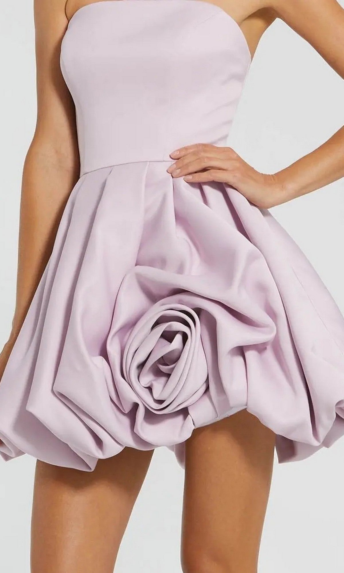 A woman wears the Red Rose Bubble-Hem Hoco Dress (Mac Duggal 20705), a strapless mini dress featuring sculpted rose-like details and a satin bubble skirt, perfect for cocktails.