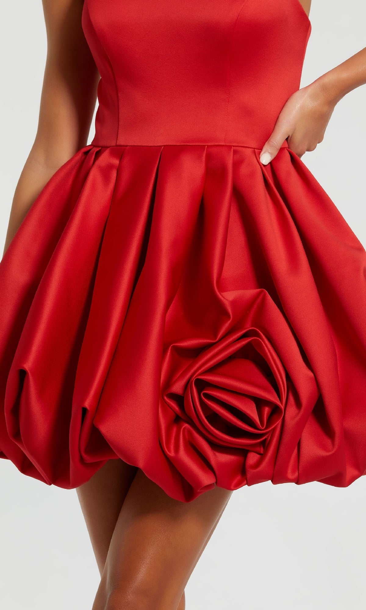 A person wears the Red Rose Bubble-Hem Hoco Dress (Mac Duggal 20705)—a sleeveless red mini with a voluminous satin a-line bubble skirt and sculpted rose detail.