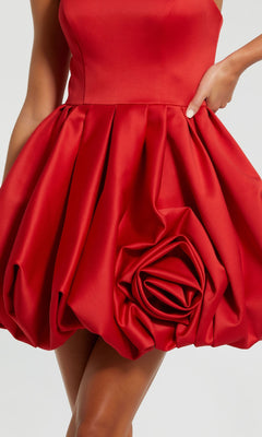 A person wears the Red Rose Bubble-Hem Hoco Dress (Mac Duggal 20705)—a sleeveless red mini with a voluminous satin a-line bubble skirt and sculpted rose detail.