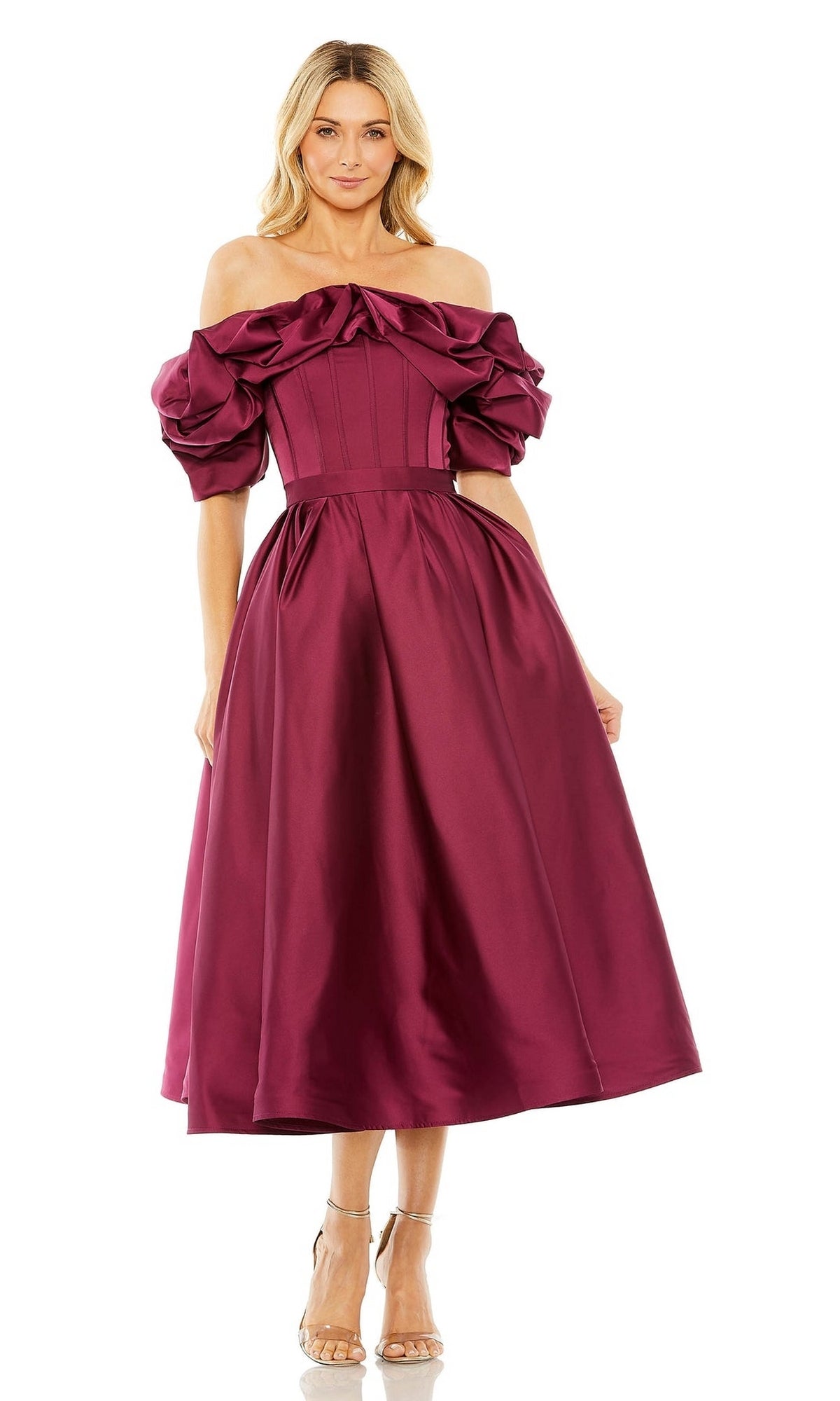 A woman stands smiling in a Mac Duggal 20706 Off-Shoulder Wedding Guest Dress, featuring burgundy puff sleeves, a fitted bodice, flared skirt, and tea-length semi-formal style.