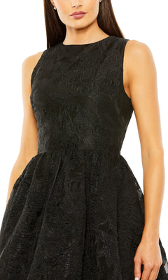 A woman wears the Brocade High-Low Formal Dress by Mac Duggal (20714), featuring a sleeveless design, textured black fabric, fitted bodice, and a flared high-low skirt.
