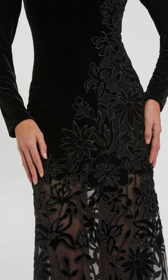 A person wearing the Mac Duggal 20746 long black velvet formal dress with sheer panels and embroidered floral patterns, shown from shoulders to knees.