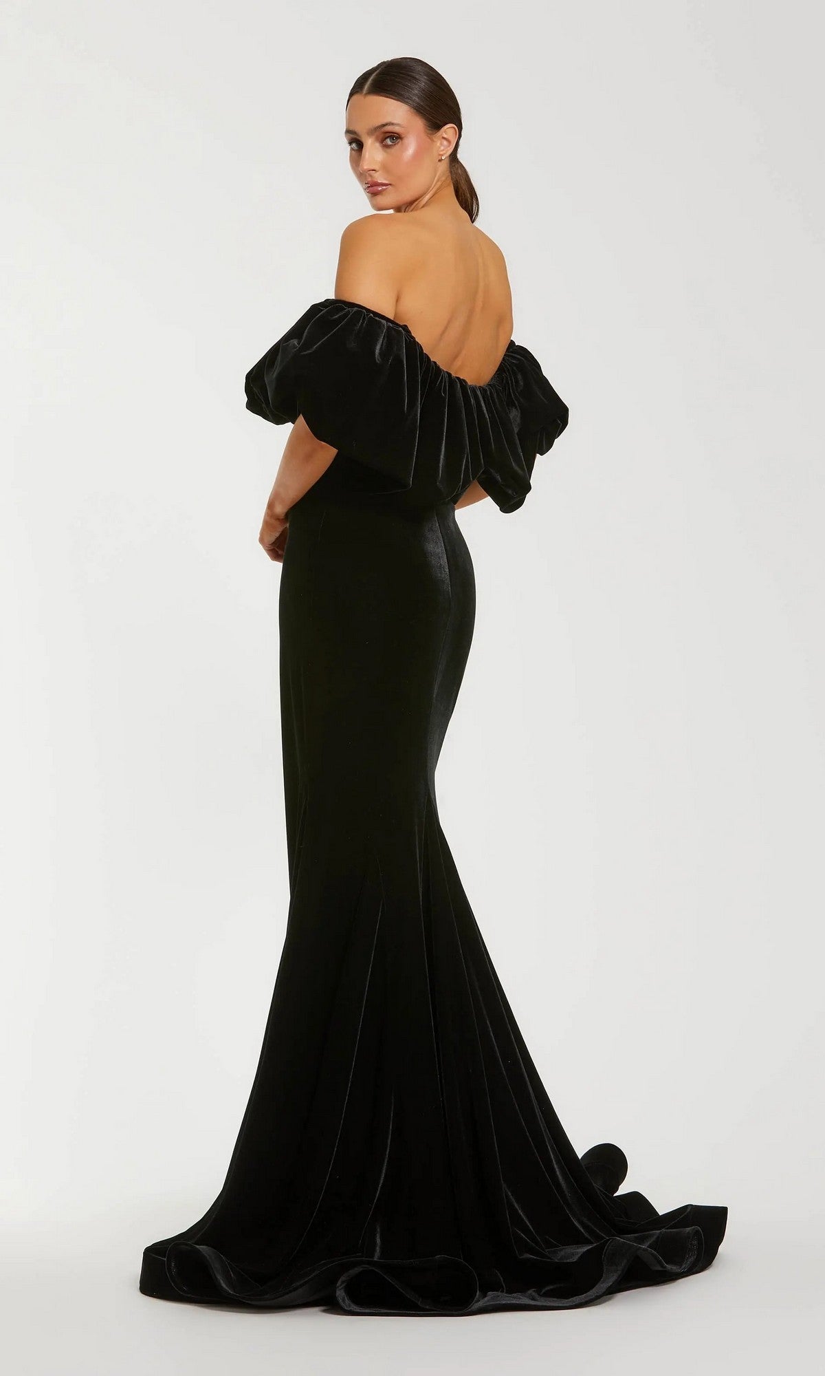 A woman models the Mac Duggal 20766, a floor-length, off-the-shoulder black velvet gown with a fitted silhouette and flared hem, showcasing classic mermaid elegance against a plain white background.