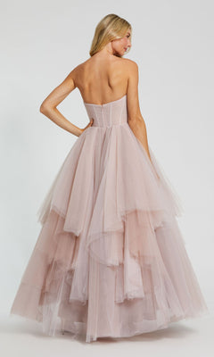 A woman is shown from the back wearing the Long Formal Dress 20772 by Mac Duggal—a strapless blush pink tulle ball gown featuring a ruched bodice and layered skirt—against a plain background.