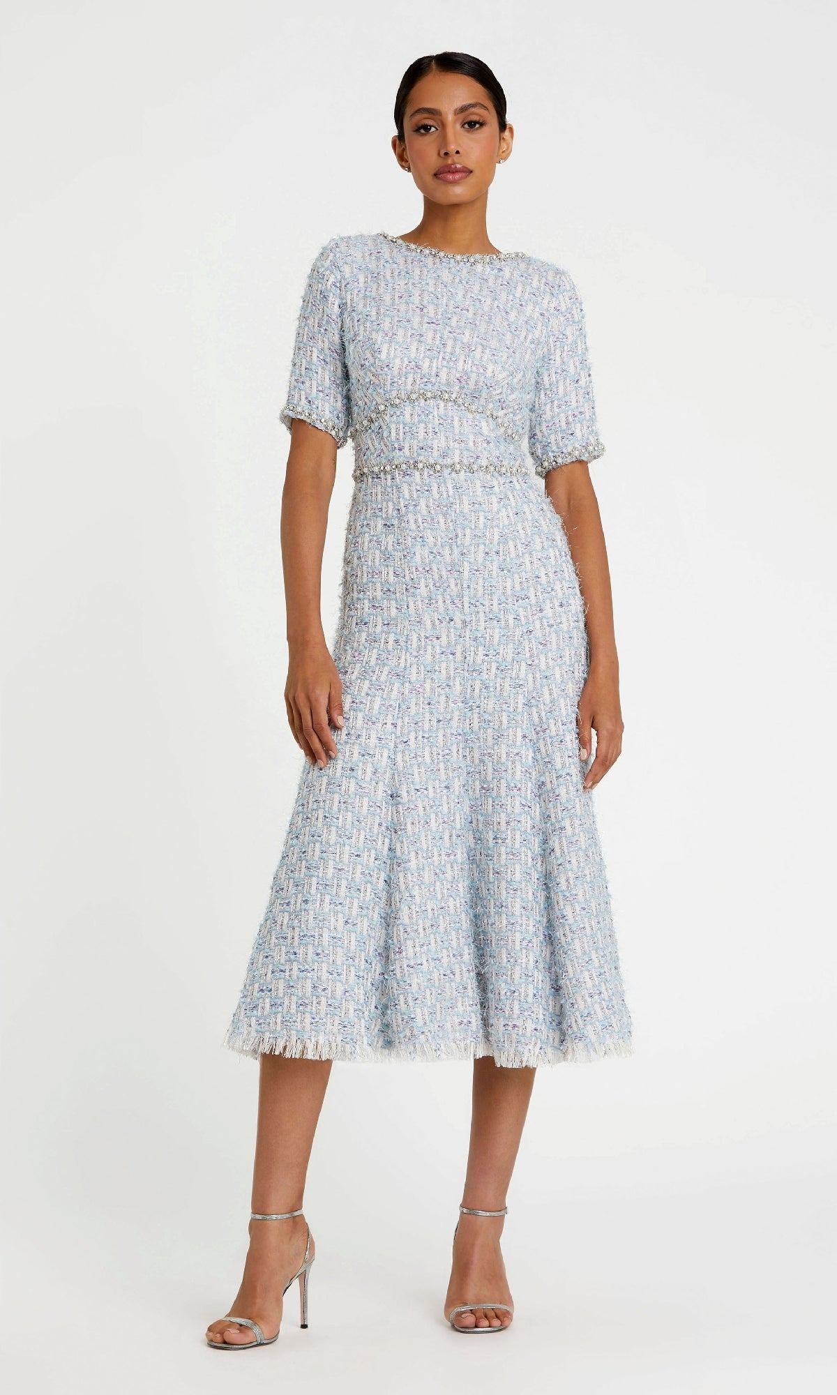 A woman wears the Mac Duggal 20806 Short Blue Wedding Guest Dress, featuring short sleeves, a fitted waist, and flared skirt, styled with silver high-heeled sandals for an elegant event-ready look.