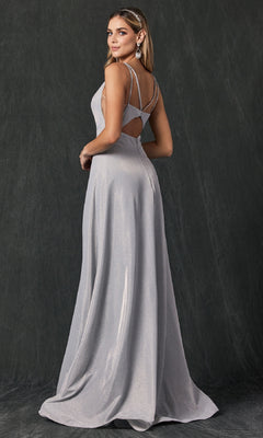 A woman wears the Juliet 208 long prom dress in silver, featuring a sleeveless design and open back, as she stands slightly turned and looks over her shoulder against a dark, textured backdrop.