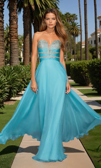 Woman in a blue evening gown with silver embellishments standing outdoors with palm trees in the background.