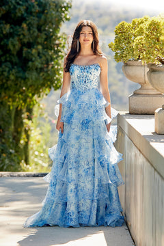A person wearing a blue Amelia Couture 2092 long prom dress with a strapless, floral design and a floor-length, ruffled skirt.