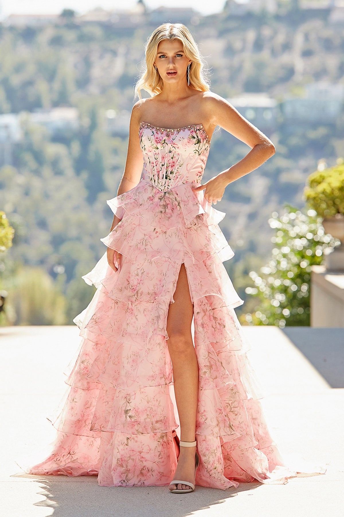 The Amelia Couture 2092 long prom dress is a strapless, floor-length floral gown with a corset bodice, tiered skirt, and a high thigh slit.