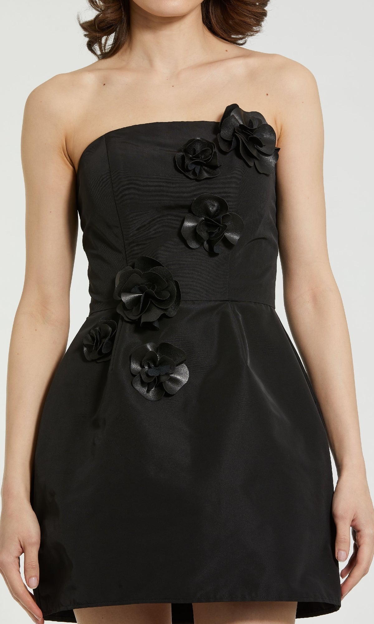 Woman wearing the Mac Duggal 21008 Strapless Black Cocktail Dress featuring a flared skirt and decorative black fabric flowers on the bodice and skirt.