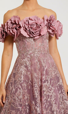 Someone is wearing the Mac Duggal 21032 long mauve formal dress, featuring an off-the-shoulder design with large fabric roses on the neckline and metallic floral embroidery on the bodice and skirt.
