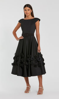 Black dress with floral rosette details on the a-line skirt worn by a model on a white background