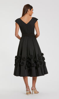 Black dress with 3D floral details on the a-line skirt, standing in front of a white background