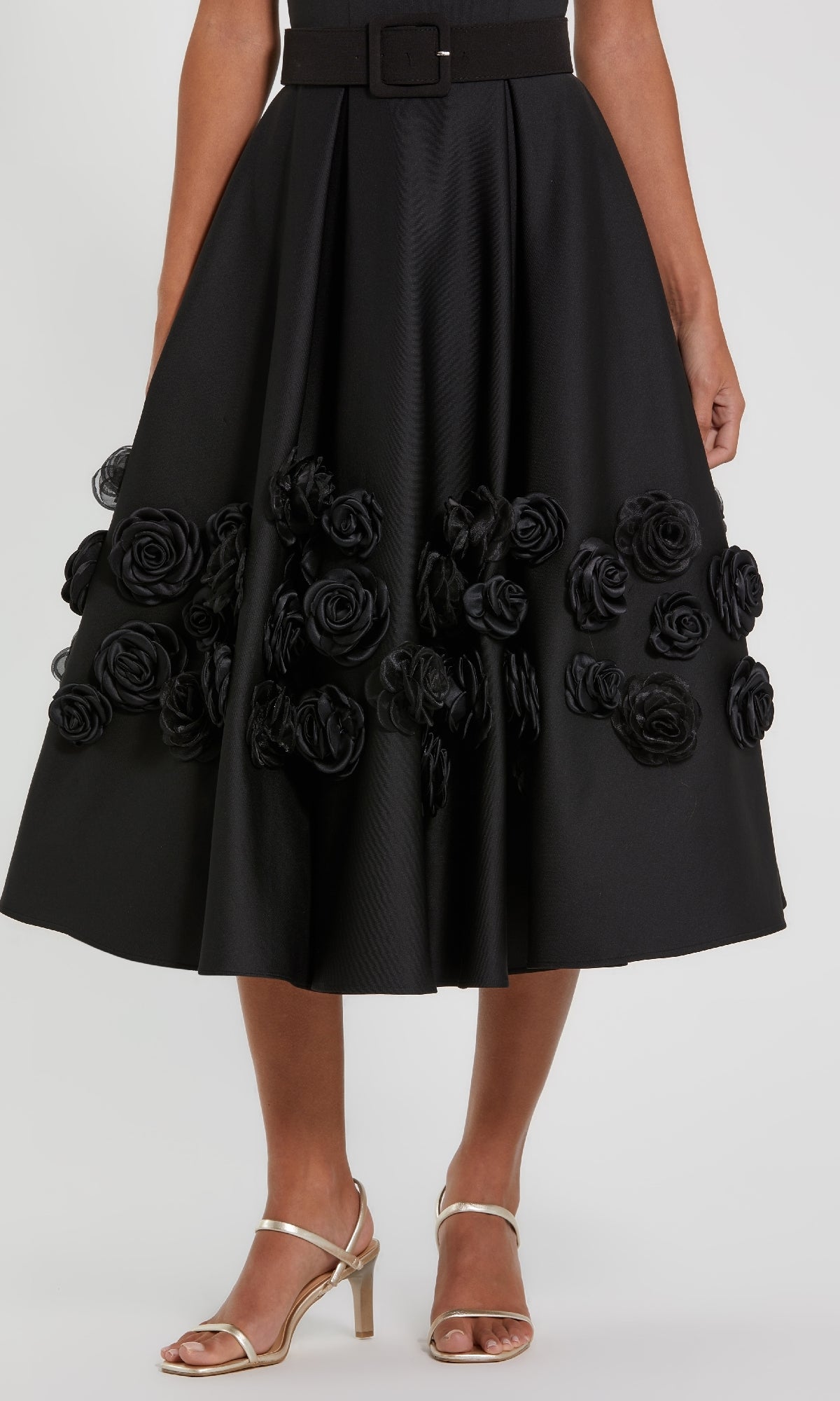 Close-up of the 3D rosette flower embellishments on the a-line skirt of a midi dress, with a white background