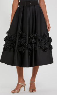 Close-up of the 3D rosette flower embellishments on the a-line skirt of a midi dress, with a white background